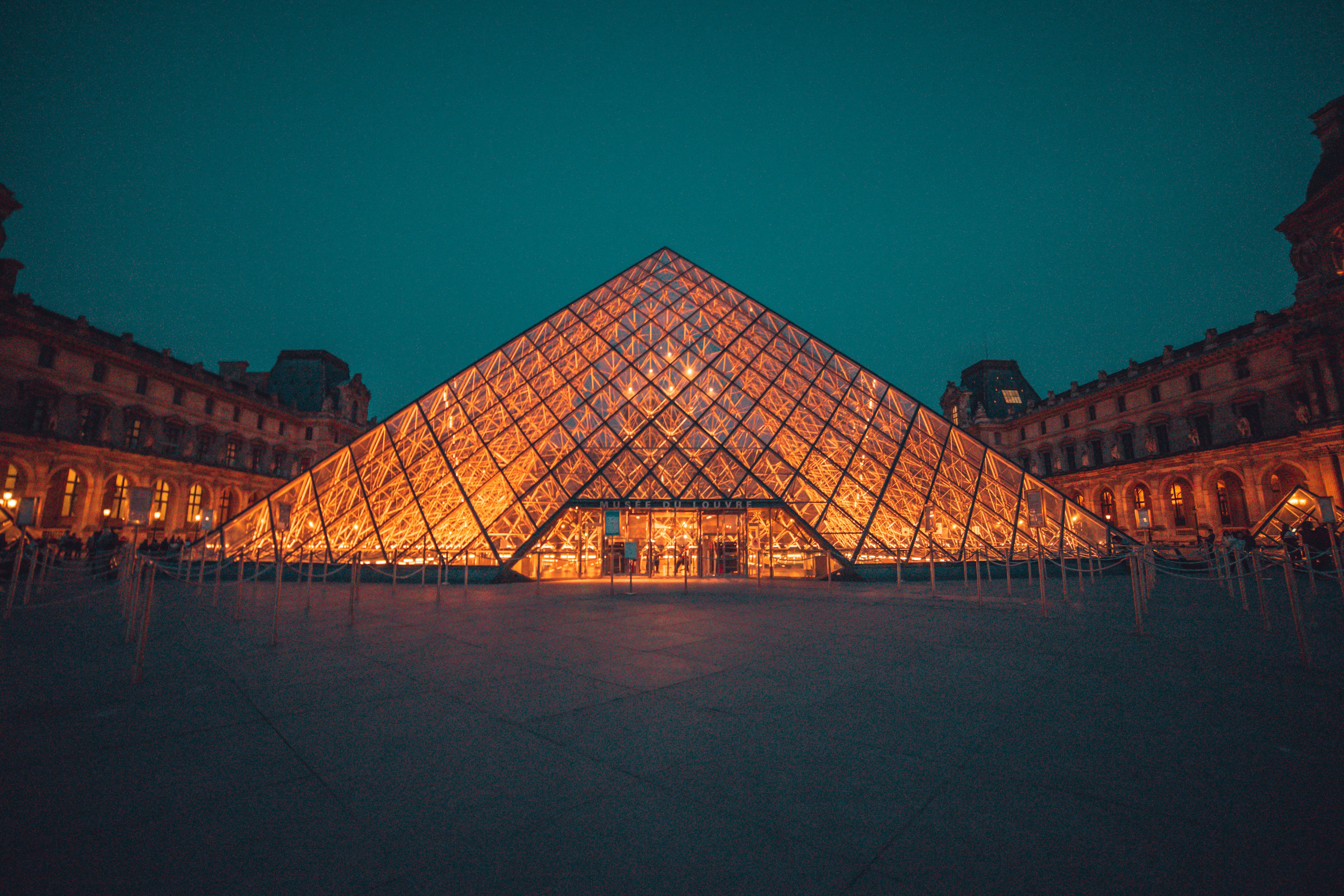 Paris Seine River Dinner Cruise - The iconic Louvre glass pyramid courtyard illuminated at blue hour dusk in Paris